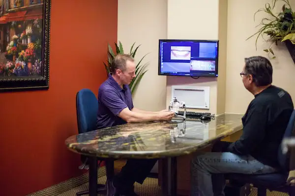 Doctor and patient sitting at office desk viewing teeth imagery at Robert F. Walker Jr. DDS in Chandler, AZ Doctor and patient sitting at office desk viewing teeth imagery at Robert F. Walker Jr. DDS in Chandler, AZ